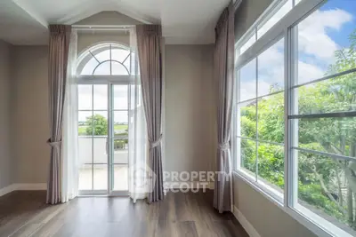 Elegant room with large windows and scenic view, featuring hardwood floors and stylish curtains.