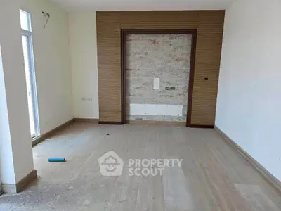 Spacious unfurnished room with large window and modern wall design, ideal for customization.