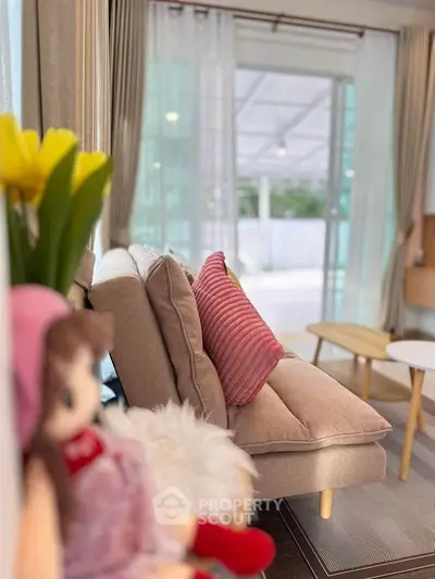 Cozy living room with stylish beige sofa and pink accents, perfect for relaxation.