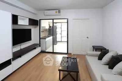 Modern living room with sleek furniture and open kitchen layout in a stylish apartment.