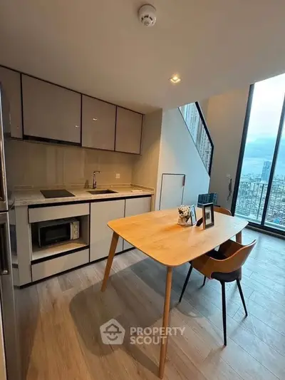 Modern kitchen with open layout and dining area featuring large windows and city view.