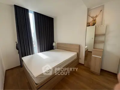 Modern bedroom with wooden flooring and stylish furniture, featuring a large window with dark curtains.
