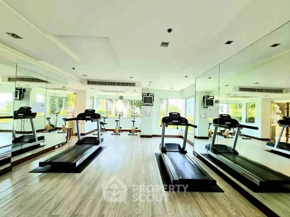 Spacious modern gym with treadmills and mirrored walls in luxury real estate property.