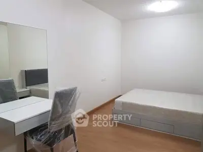 Minimalist bedroom with bed, chair, and mirror in modern apartment.