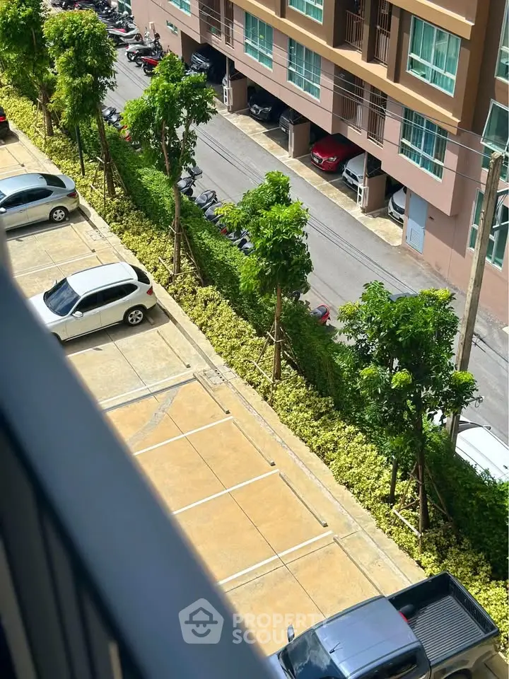 Aerial view of residential building parking area with lush greenery and parked cars.