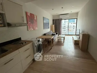 Modern open-layout living room with kitchen and balcony view in urban apartment.