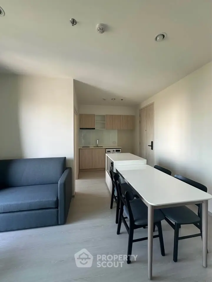 Modern apartment interior with open kitchen and dining area, featuring sleek furniture and minimalist design.