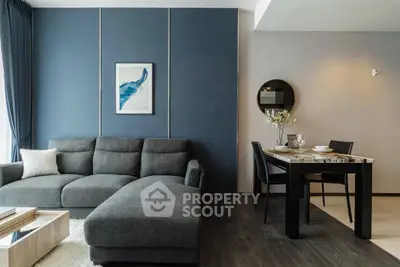 Modern living room with stylish gray sofa and elegant dining area, featuring contemporary decor and natural lighting.