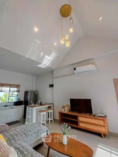 Spacious modern living room with high ceiling and stylish lighting, featuring open kitchen and cozy seating area.