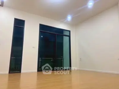 Spacious empty room with large windows and wooden flooring, perfect for customization.