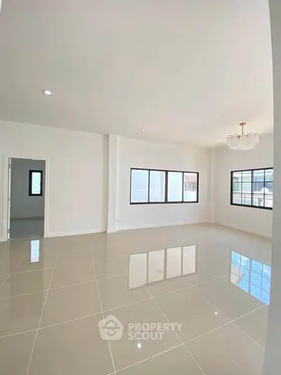 Spacious and bright living room with large windows and modern tile flooring.
