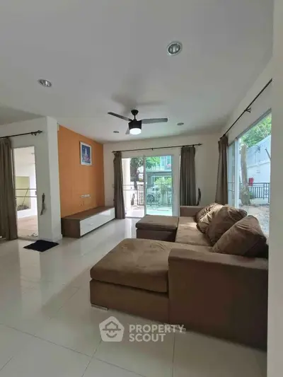 Spacious living room with large sofa and natural light, perfect for relaxation.