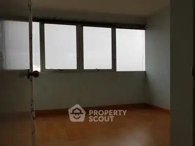 Spacious empty room with large windows and wooden flooring, ideal for customization.