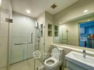 Modern bathroom with glass shower and sleek fixtures in contemporary apartment.