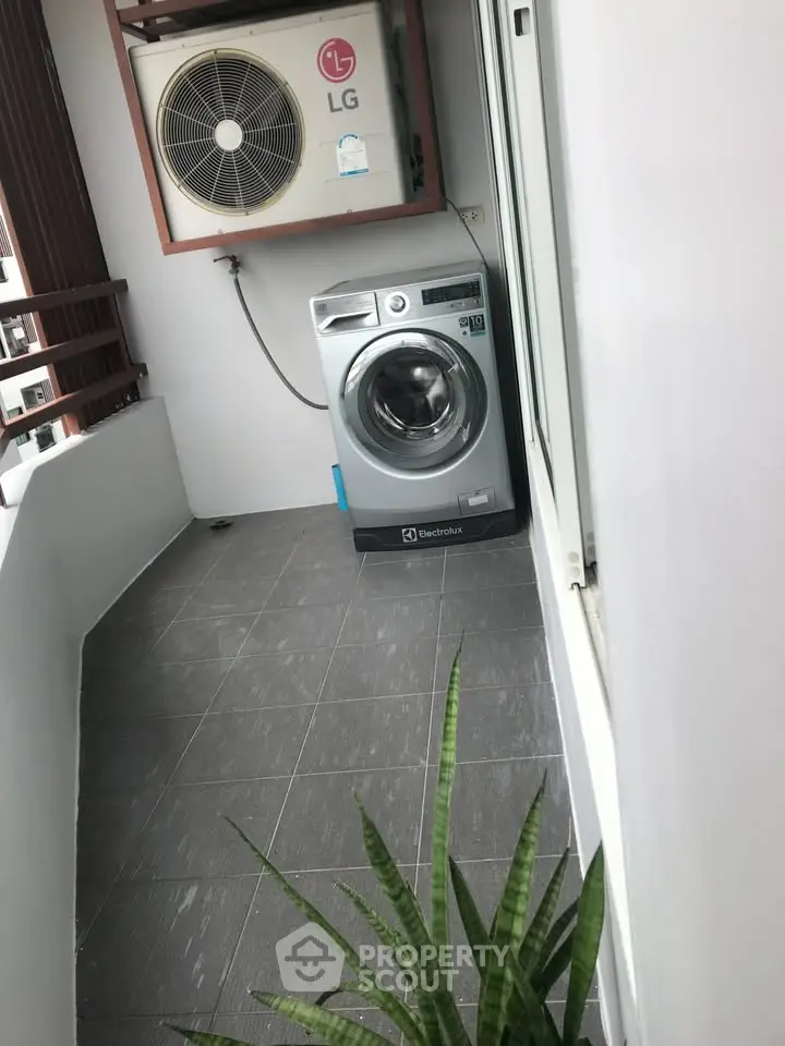 Modern balcony with washing machine and air conditioning unit, sleek design.