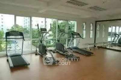 Spacious gym with modern equipment and large windows offering a scenic view.