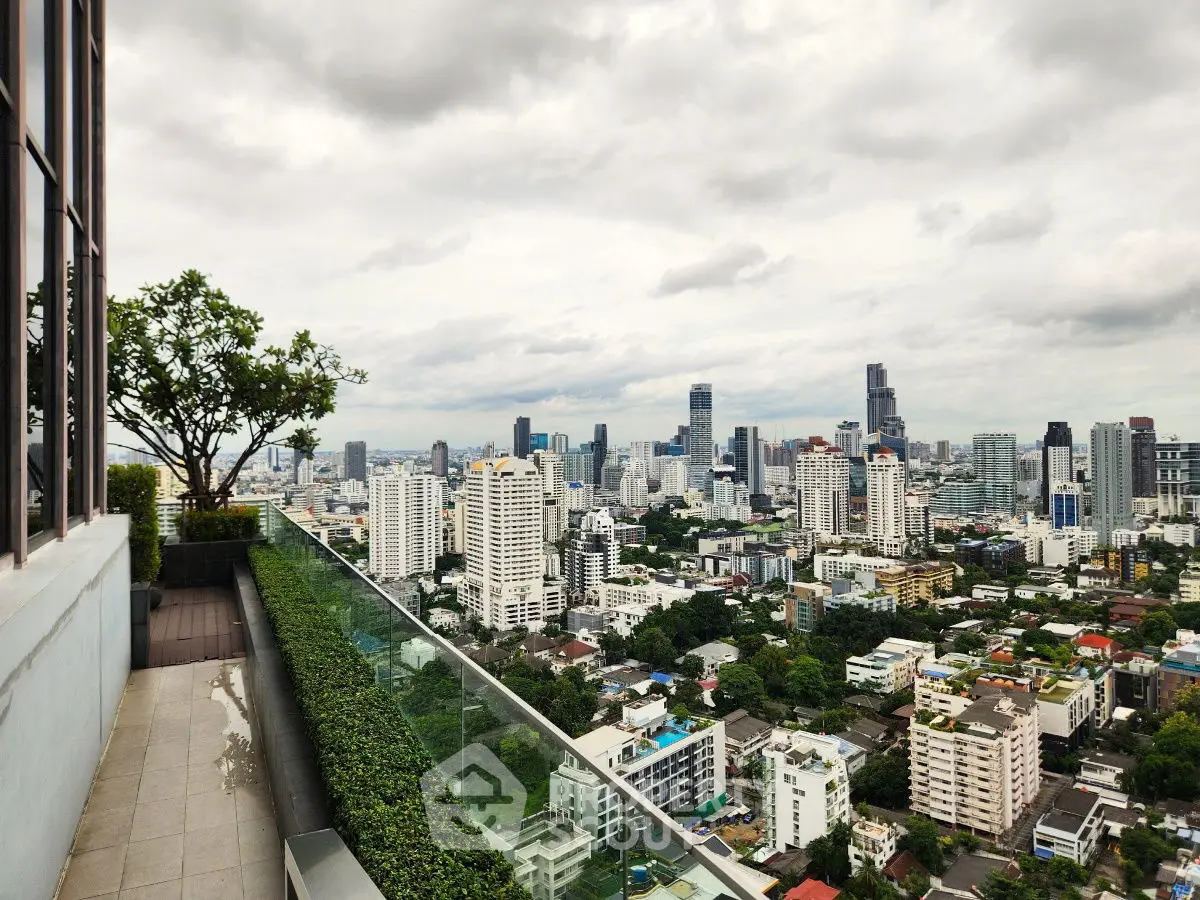 Stunning cityscape view from a high-rise balcony with lush greenery.