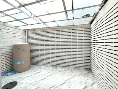 Spacious enclosed outdoor area with marble flooring and water tank, ideal for storage or utility use.