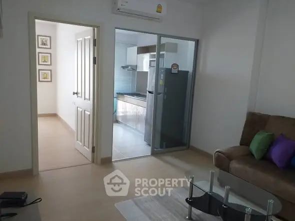 Modern apartment interior with open living room and kitchen layout, featuring sleek furniture and bright lighting.