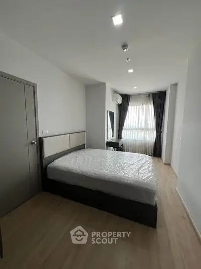 Modern bedroom with large window and minimalist decor in a stylish apartment.