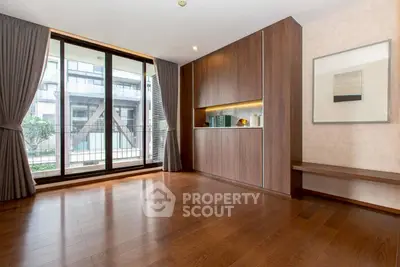 Spacious modern living room with large windows and elegant wood flooring.