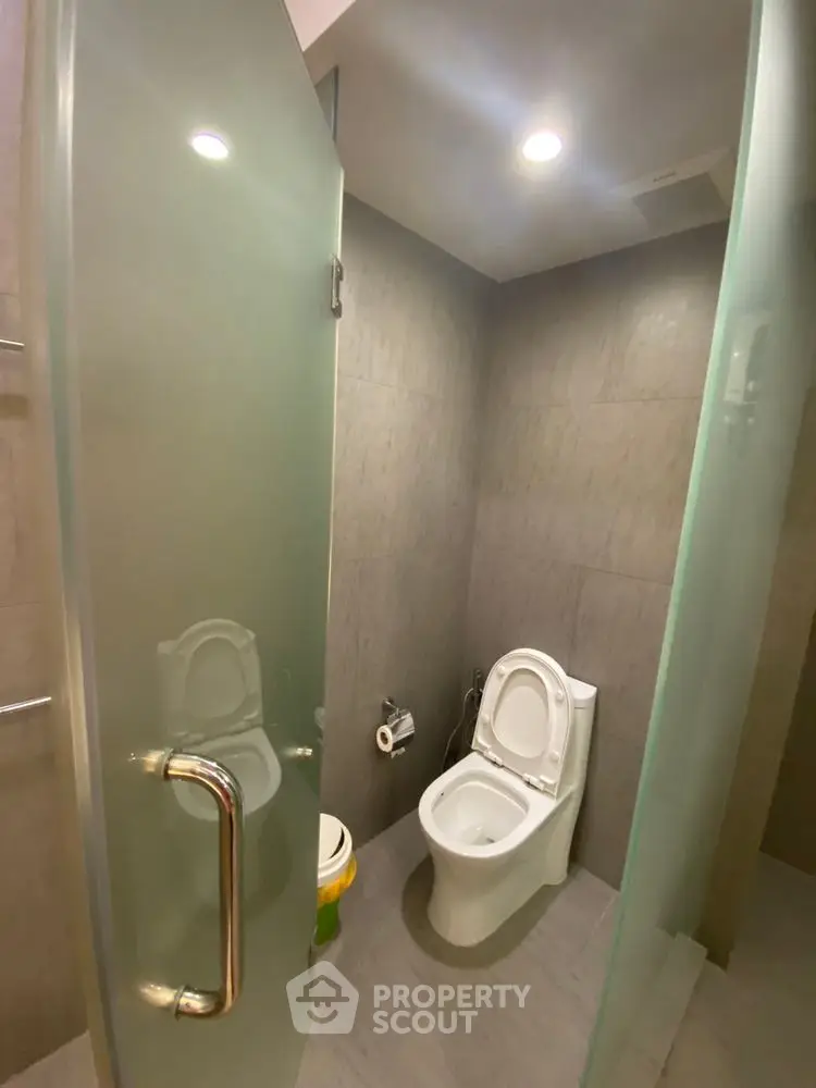 Modern bathroom with frosted glass door and sleek toilet design