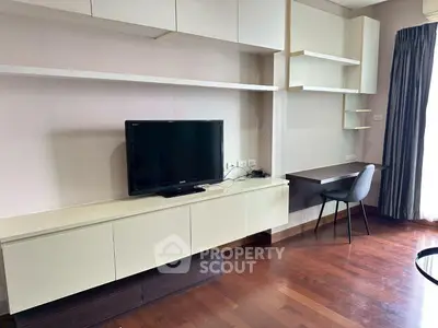 Modern living room with sleek TV setup and stylish study area, featuring elegant wooden flooring.
