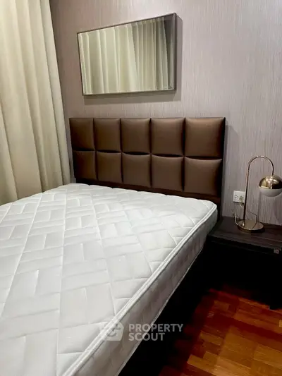 Cozy bedroom with modern decor and plush headboard, perfect for relaxation.