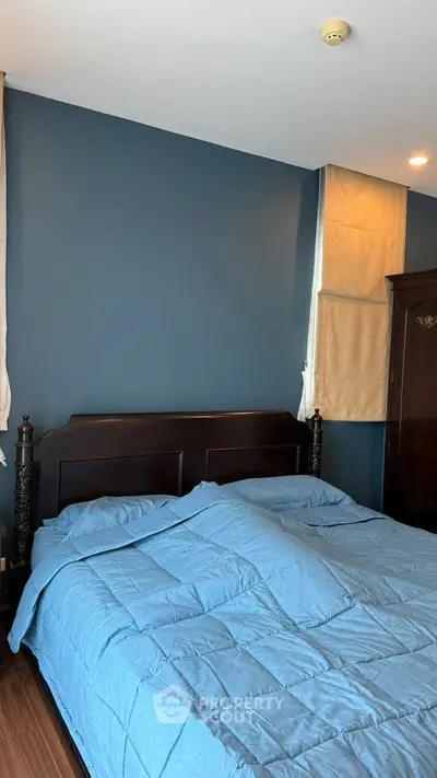 Cozy bedroom with elegant dark wood bed frame and blue bedding, perfect for restful nights.