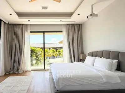 Luxurious bedroom with large windows and elegant decor, offering a serene view of lush greenery.