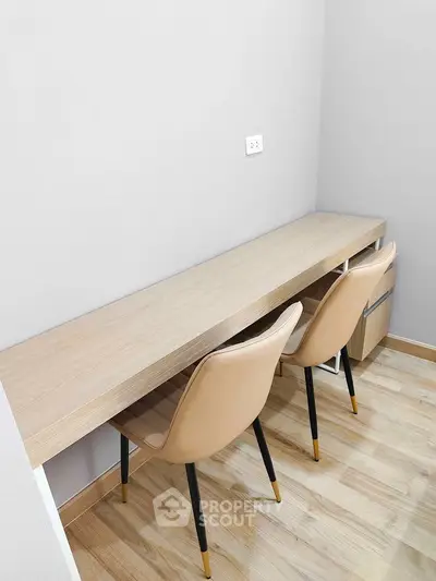 Modern study area with sleek desk and stylish chairs on wooden flooring.