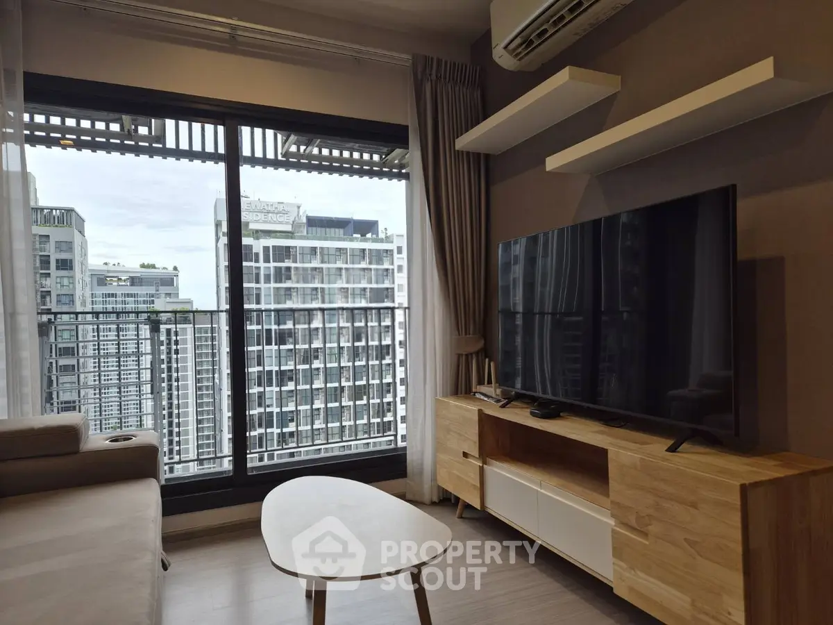 Modern living room with large TV and city view from balcony