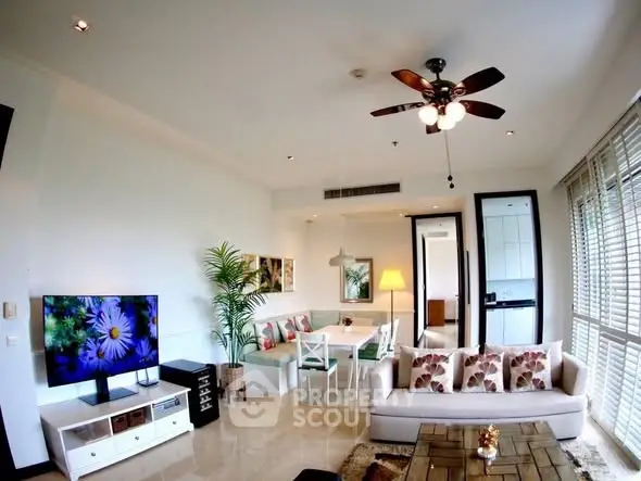 Spacious living room with modern decor and natural light, featuring a ceiling fan and stylish furniture.