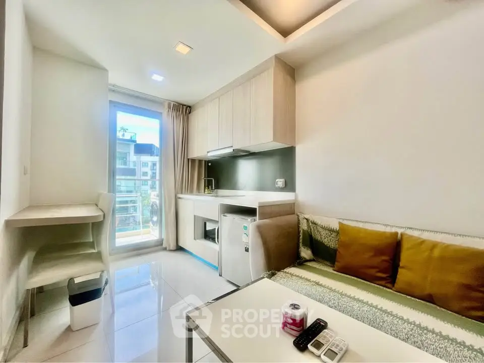 Modern living room with sleek design, featuring a compact kitchen and bright natural light from large windows.