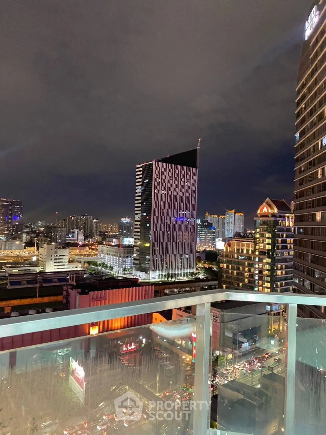 Stunning cityscape view from a modern balcony at night, showcasing vibrant urban lights and skyline.