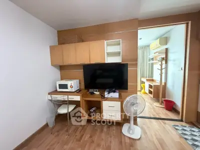 Modern living room with wooden flooring, TV, and compact workspace in cozy apartment.