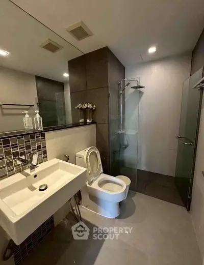 Modern bathroom with sleek design, featuring a glass shower and stylish fixtures.