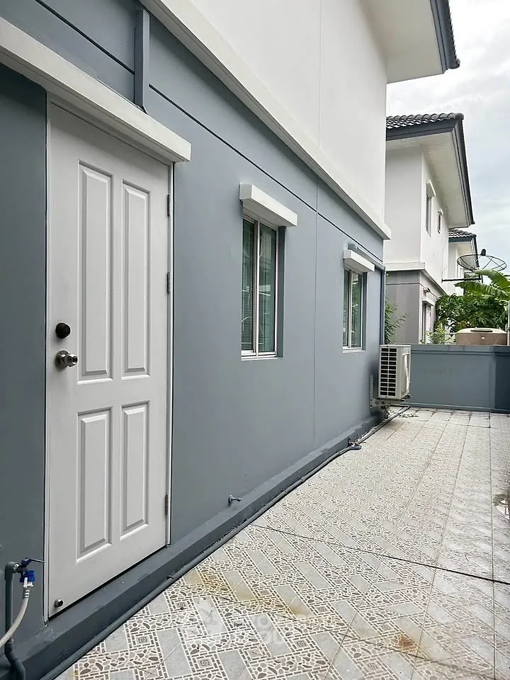 Modern exterior of a residential building with tiled patio and air conditioning unit.
