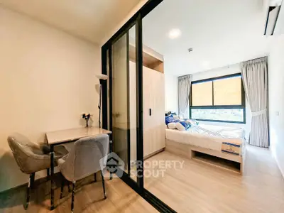 Modern bedroom with sliding glass doors and cozy dining area, featuring natural light and elegant decor.
