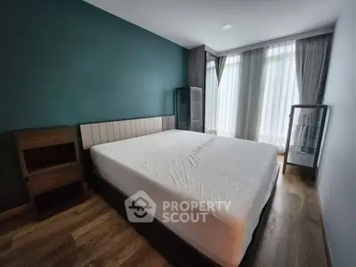 Spacious bedroom with large bed and modern decor, featuring wooden flooring and natural light.