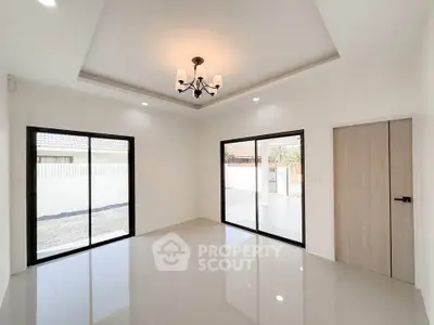 Spacious modern living room with elegant chandelier and large windows for natural light.