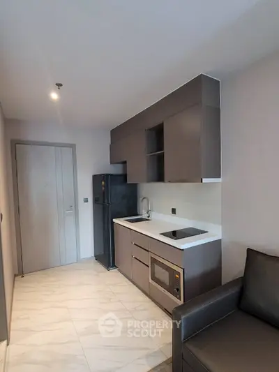 Modern compact kitchen with sleek cabinetry and integrated appliances in a stylish apartment.