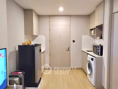 Modern apartment interior with washing machine and microwave in compact kitchen area.