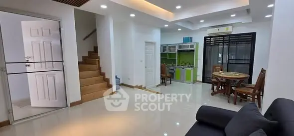 Spacious open-plan living room with modern kitchen and dining area, featuring sleek design and ample natural light.