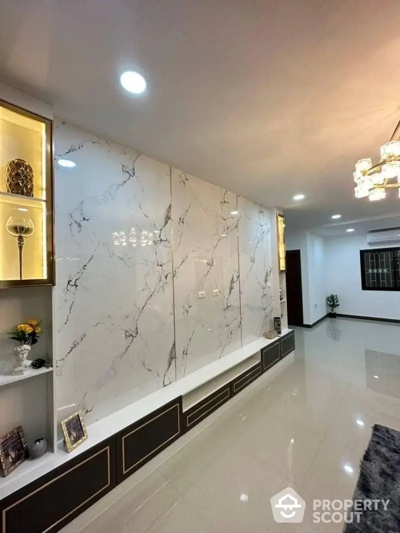 Luxurious living room with marble walls, elegant chandeliers, and polished tile flooring, offering a sophisticated space for relaxation and entertainment.