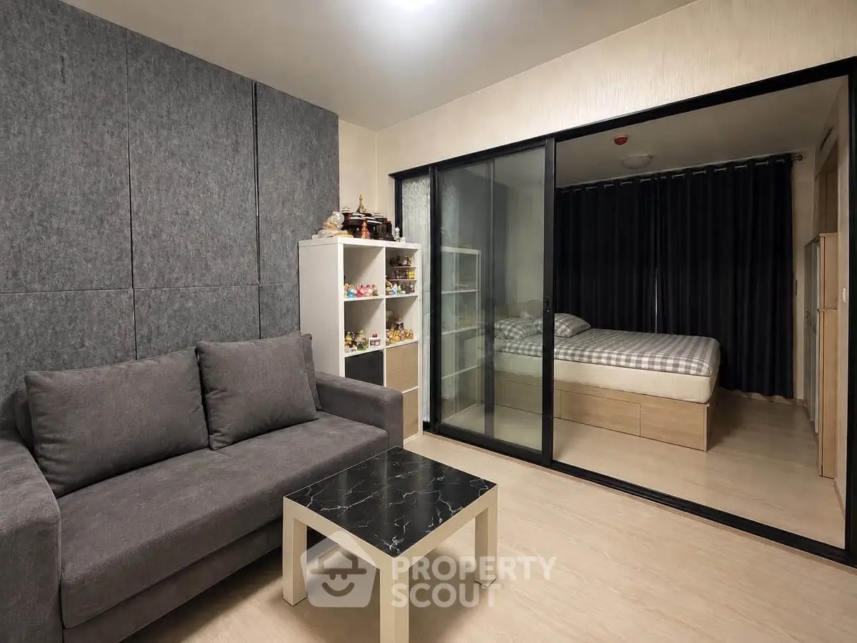 Modern studio apartment with cozy living area and sliding glass doors to bedroom.