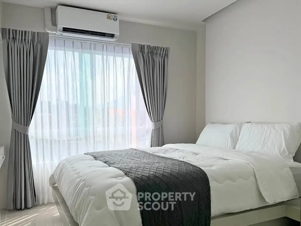 Modern bedroom with elegant curtains and air conditioning, featuring a cozy bed with white linens.