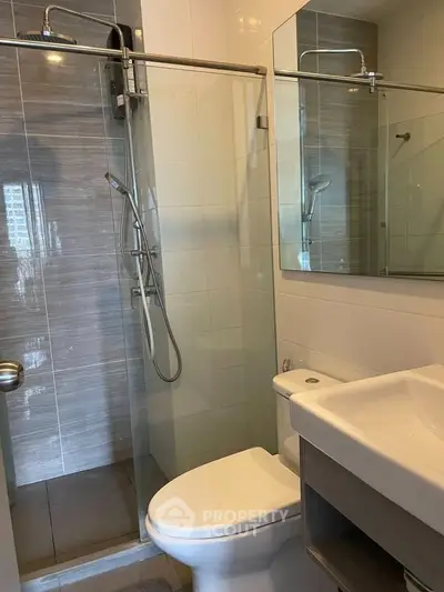 Modern bathroom with glass shower and sleek fixtures in contemporary apartment.