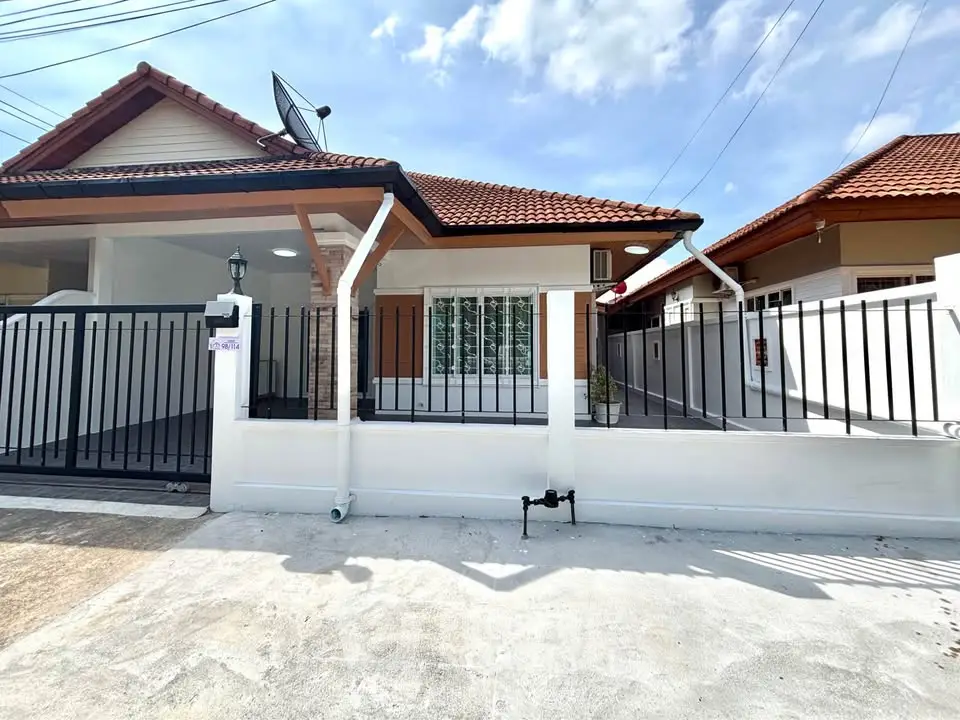 Charming single-story house with red-tiled roof and gated entrance under a clear blue sky.