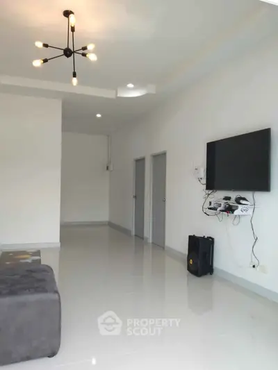 Spacious modern living room with sleek design and mounted TV, perfect for entertainment.